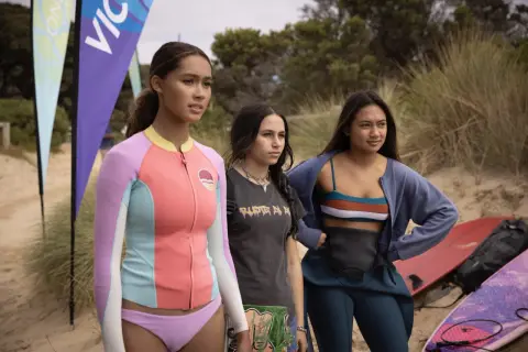 Drei junge Frauen stehen am Strand, bereit für die Wellen. Savannah La Rain und ihre Freundinnen warten auf den perfekten Surf.