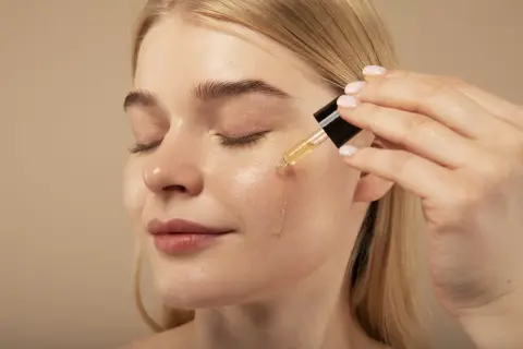 Kobieta aplikuje serum na twarz. Pamiętaj, retinol z czym nie łączyć, by uniknąć podrażnień.