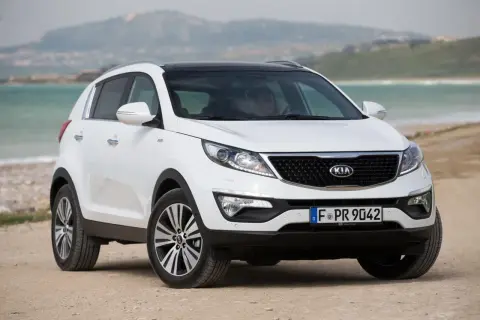 Biały Kia Sportage 2014 na plaży, gotowy na przygodę nad morzem.