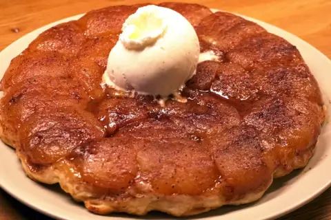 En gyllene tarte tatin med en kula vaniljglass som smälter över de karamelliserade äpplena.