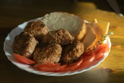 Talerz z kotletami mielonymi, kromkami chleba, pomidorami i serem. Idealny na szybki obiad, choć warto sprawdzić kotlet mielony kcal.