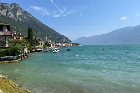 Vista sul lago con montagne sullo sfondo, barche e case colorate. Un vero gargnano geheimtipp.
