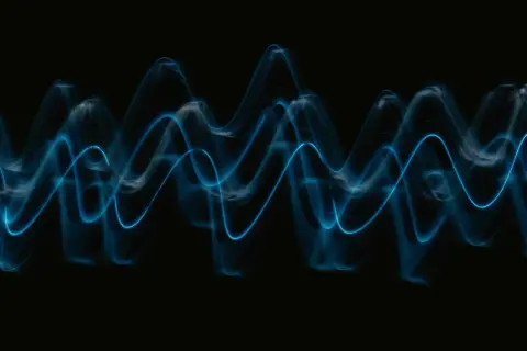Abstract blue light trails form wave patterns on a black background, visualizing the sound waves that play wav files.