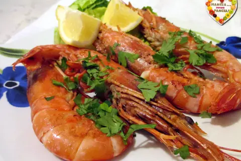 Assiette de gambas grillées, garnie de persil frais et de quartiers de citron. Une belle idée pour une recette gambas légère et savoureuse.