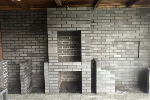 Nowy, murowany prosty grill z cegły czeka na pierwsze rozpalenie. Wygodny, z miejscem na drewno i akcesoria.