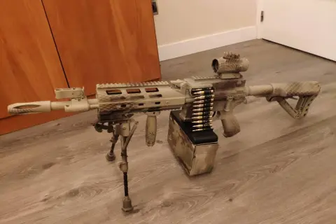 Réplica de airsoft con camuflaje personalizado. El detalle de pintar replica airsoft es impresionante, con un cargador de cinta y mira holográfica.