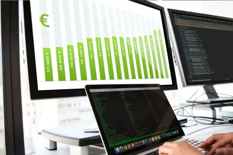 Balkendiagramm zeigt steigende Gehälter für Informatiker, von 37.900 € bis über 50.000 €. Ein Laptop mit Code ist im Vordergrund zu sehen.