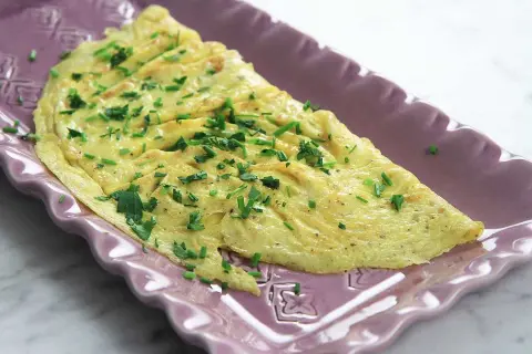 En perfekt vikt omelett med gräslök, redo att serveras. Ett enkelt omelett recept för en snabb och god måltid.