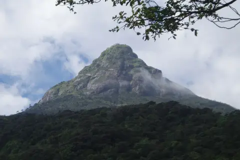 Adams Peak reser sig majestätiskt, klädd i grönska och omfamnad av moln.