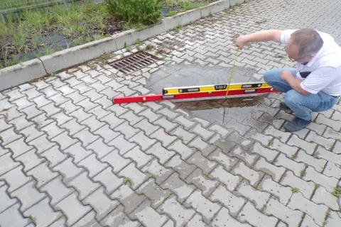 Mężczyzna sprawdza poziom wody na chodniku z kostki brukowej.