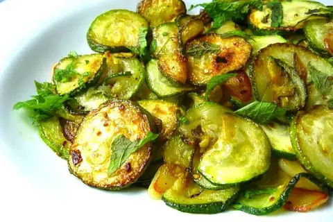 Zucchine alla scapece ricetta napoletana: fette di zucchine fritte e marinate con menta fresca, un contorno saporito e profumato.