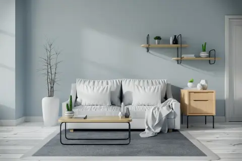 Soggiorno moderno con divano bianco, tavolino in legno e pareti color carta da zucchero.