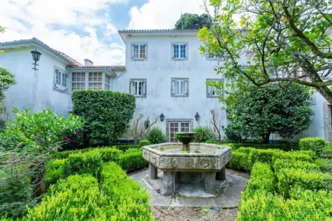 Jardín del pazo do casal con fuente de piedra y setos verdes.