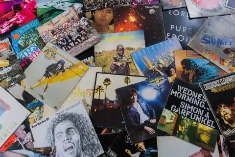 Bunte Schallplatten zeigen, welche Musikrichtungen es gibt: Rock von AC/DC, Pop von Genesis, Reggae von Bob Marley und mehr.