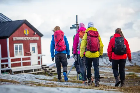 Vandringsgrupp närmar sig STF Sylarnas fjällstation. Vackert höstlandskap med molnig himmel.