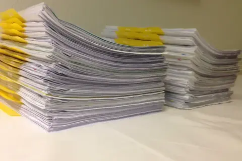 Stosy dokumentów, żółte zakładki. Orzeczenie o potrzebie kształcenia specjalnego otwiera drogę do wsparcia edukacyjnego.