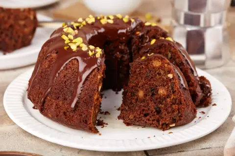 Puszysta babka na oleju, polana czekoladą i posypana pistacjami, kusi swoim wyglądem. Idealna na deser.