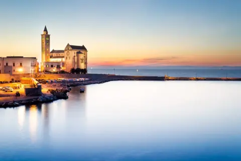 Tramonto sul porto di Trani, con la cattedrale illuminata che domina il paesaggio. Un'incantevole vista dei dintorni di Trani.