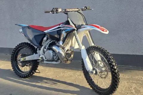 Motocykl crossowy Husqvarna CR 250 z czerwonym siedzeniem i czarnymi elementami, gotowy do jazdy po torze.
