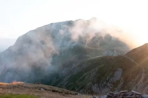 Sentier brumeux sur les hauteurs, un aperçu du tour du Mont-Blanc en 3 jours. Lumière dorée filtrant à travers les nuages.