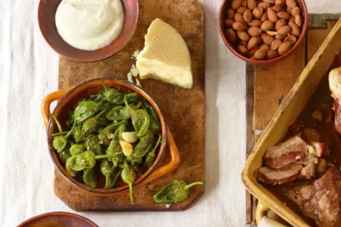Eine **spanische Tapas Liste** mit gebratenen Pimientos, Mandeln, Käse und einem Braten.