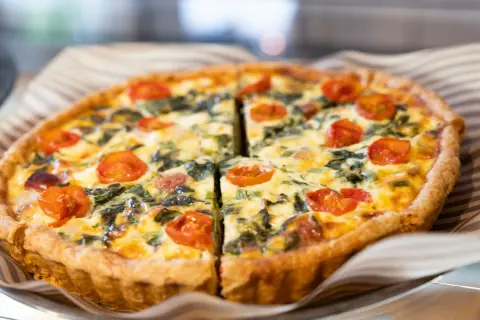 Torta salata con pomodorini e spinaci, perfetta per il tempo di cottura torta salata forno ventilato. Dorata e invitante.