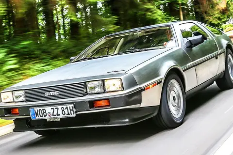 Silberner DeLorean DMC-12 rast durch eine grüne Allee.