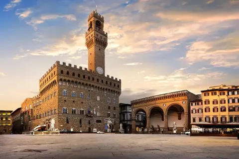 Il maestoso Palazzo Vecchio domina Piazza della Signoria, con la sua torre imponente che svetta nel cielo al tramonto.