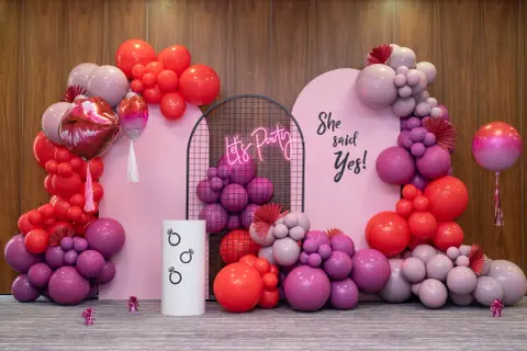 Różowa girlanda balonowa tworzy tło dla imprezy. Napis "She said Yes!" i neonowe "Let's Party" dodają uroku.