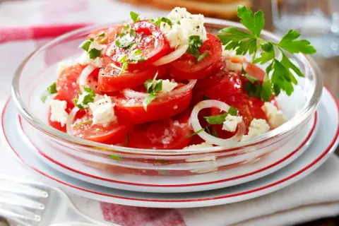 Frischer tomatensalat mit feta, Zwiebeln und Petersilie, garniert mit Pfeffer und Salz. Ein leichter Genuss.