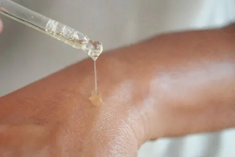 Kropla serum z niacynamidem 5% spada na skórę, nawilżając ją i odżywiając.