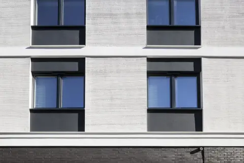 Moderne Fassade mit Klinker und Putz. Fenster mit dunklen Rahmen und blauen Scheiben.