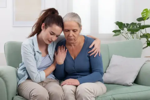 Giovane donna conforta madre anziana, un abbraccio di sostegno per il permesso per lutto suocero.