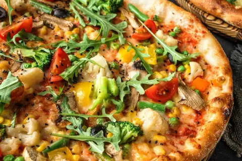 Apetyczna pizza bez mięsa z brokułami, pomidorkami, kukurydzą i rukolą.