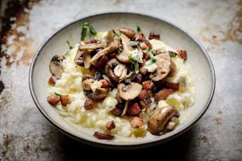En krämig risotto med kyckling, toppad med champinjoner, knaperstekt bacon och en touch av blåmögelost. En riktig smakupplevelse!