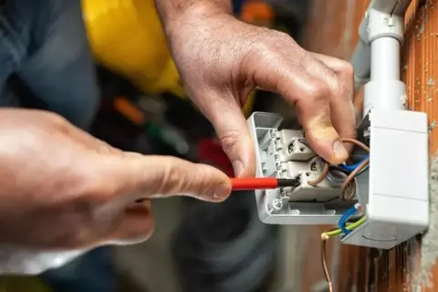 Elettricista collega cavi a una presa, mostrando le differenze tra i tipi di connessione.