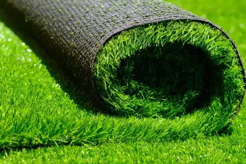 A rolled-up section of artificial grass lies on a bed of lush green turf, hinting at how to install artificial grass for a perfect lawn.