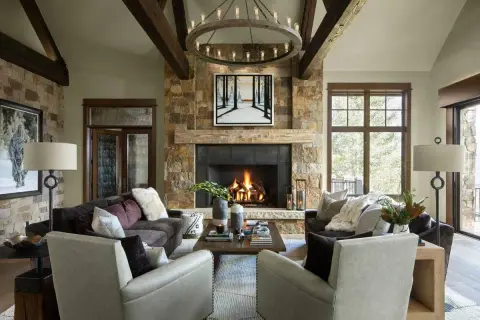 A cozy living room with a stone fireplace, exposed wooden beams, and plush seating embodies rustic interior design.