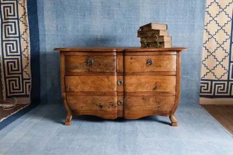 Cómoda antigua de madera con libros apilados, lista para restaurar muebles.