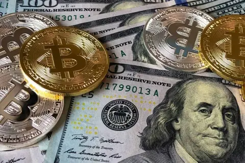 Złote i srebrne monety Bitcoin leżą na banknotach dolarowych. To obraz, który inspiruje do refleksji nad przyszłością pieniędzy i cytatami o finansach.