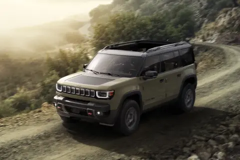 Jeep Recon in verde militare affronta un sentiero sterrato in montagna, pronto per ogni avventura.