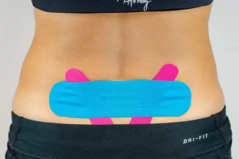 LWS tapen: Blaues und pinkes Kinesio-Tape stützt den unteren Rücken für mehr Stabilität und Schmerzlinderung.