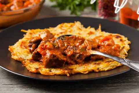 Gulasz do placka po węgiersku, bogaty i aromatyczny, podany na chrupiącym placku ziemniaczanym.