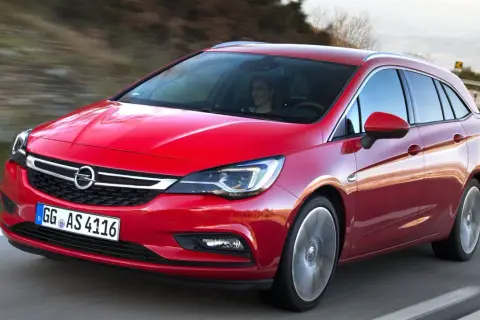 Röd Opel Astra kombi 2016 körs på en väg. En kvinna syns bakom ratten. Kanske ett problem med bilen?