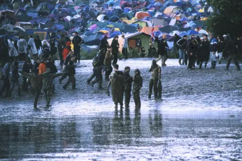 Muddy field with tents and people at Radiohead's iconic Glastonbury 1997 performance.