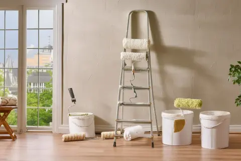 Préparation pour nettoyer mur intérieur crépi avant peinture : rouleaux, seaux et échelle sont prêts.