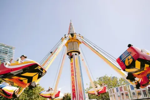 Karuzela "Hurricane" wesoło kręci się na tle błękitnego nieba, przypominając polski Disneyland.