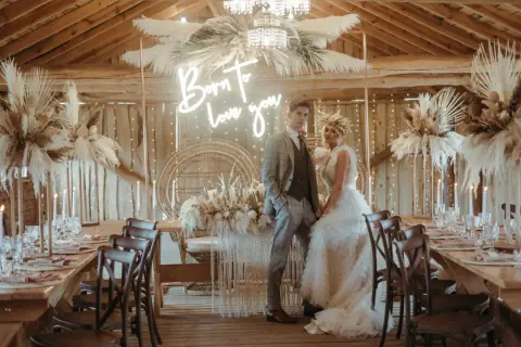 Eleganckie wesele w stodole: boho dekoracje z traw pampasowych, neon "Born to love you" i para młoda.