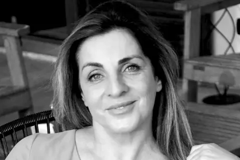 Ritratto in bianco e nero di una donna con capelli castani lunghi e mossi, occhi azzurri e un sorriso leggero. Sembra pensierosa, come se fosse andata a convivere ma non fosse felice.