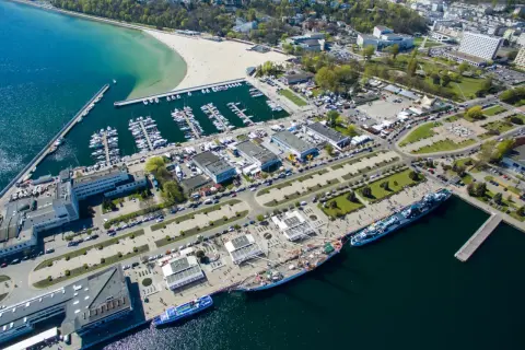 Gdynia co zobaczyć: malownicza plaża, pełny jachtów port, statki i miejska panorama. Idealne miejsce na spacer i podziwianie widoków.